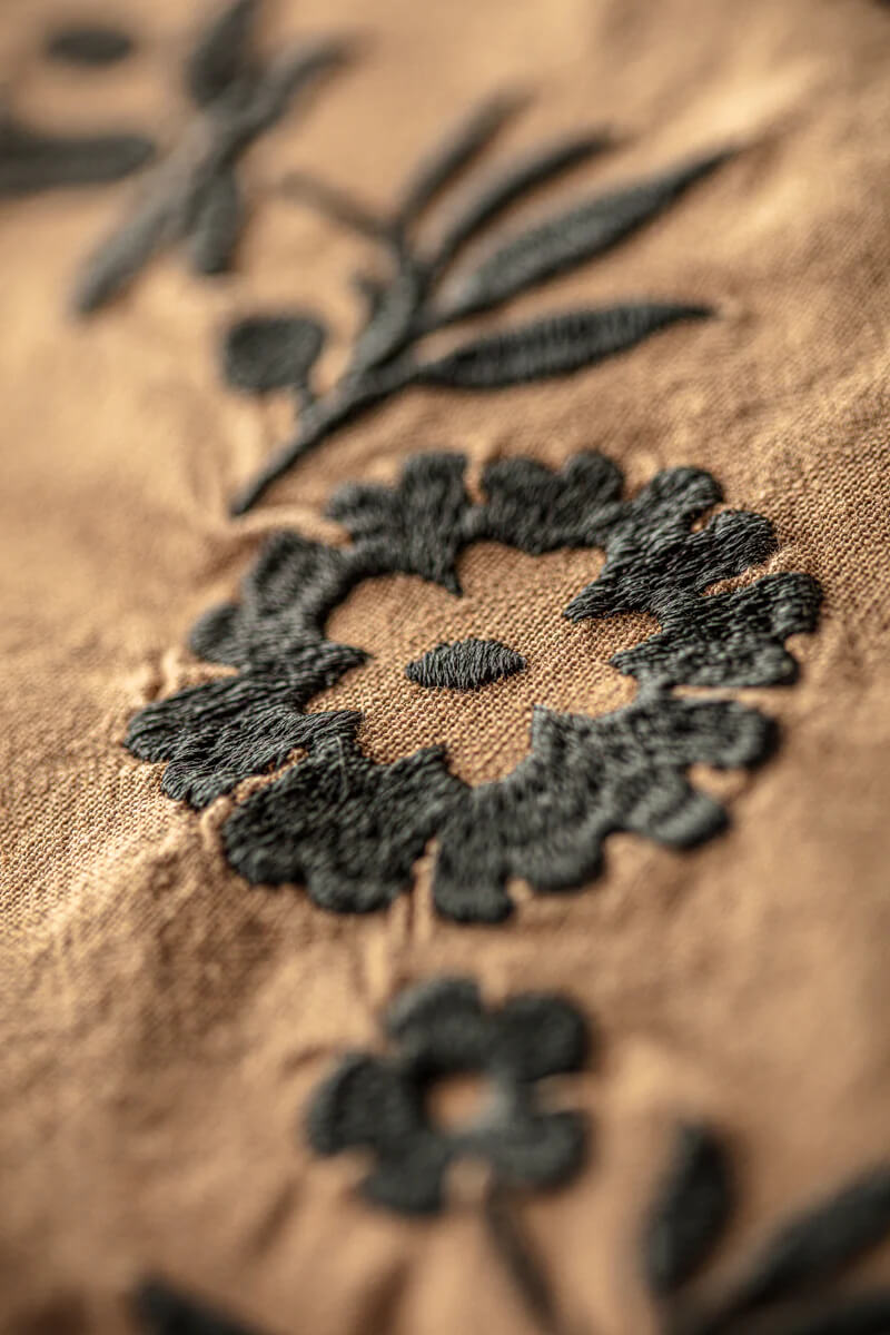 Close-up of black floral embroidery on brown fabric