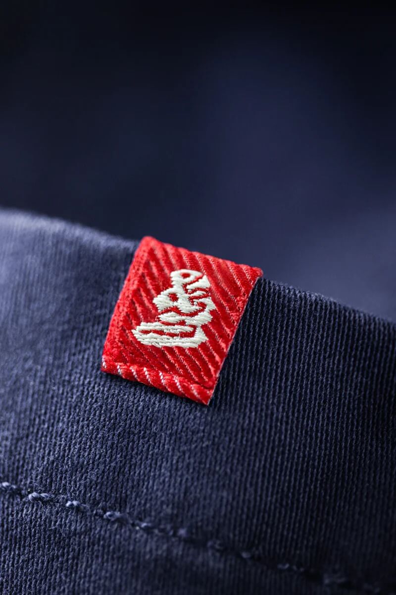 Close-up of a red label with white logo on a dark fabric background