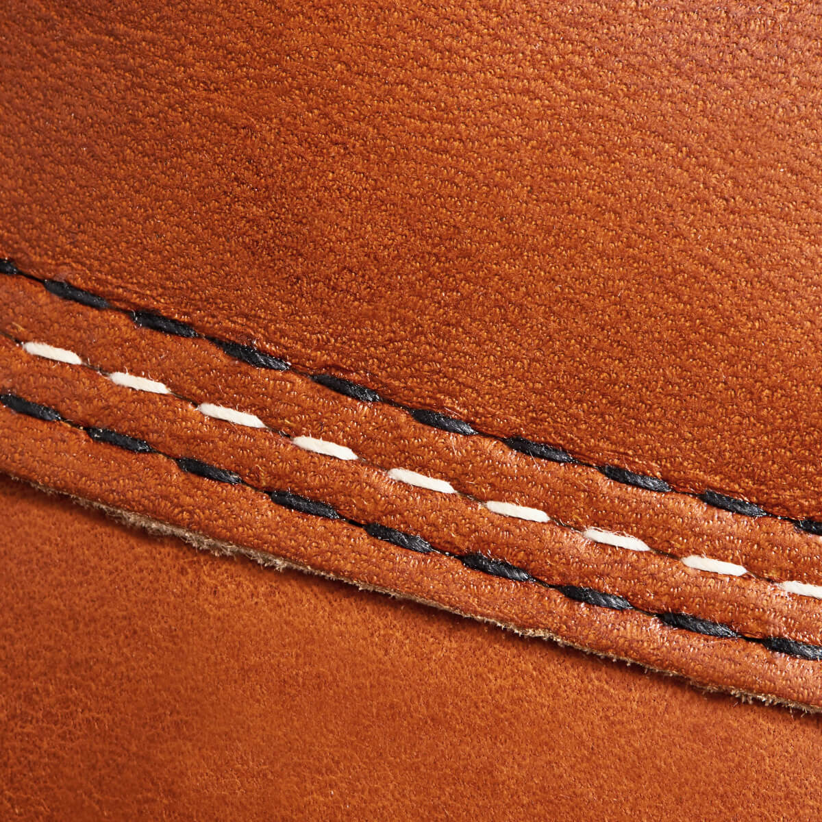 Close-up of brown leather with black and white stitching