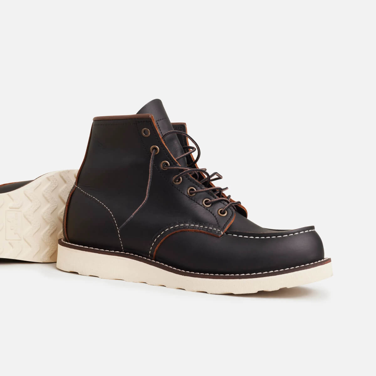 Black leather boot with white sole on a light gray background