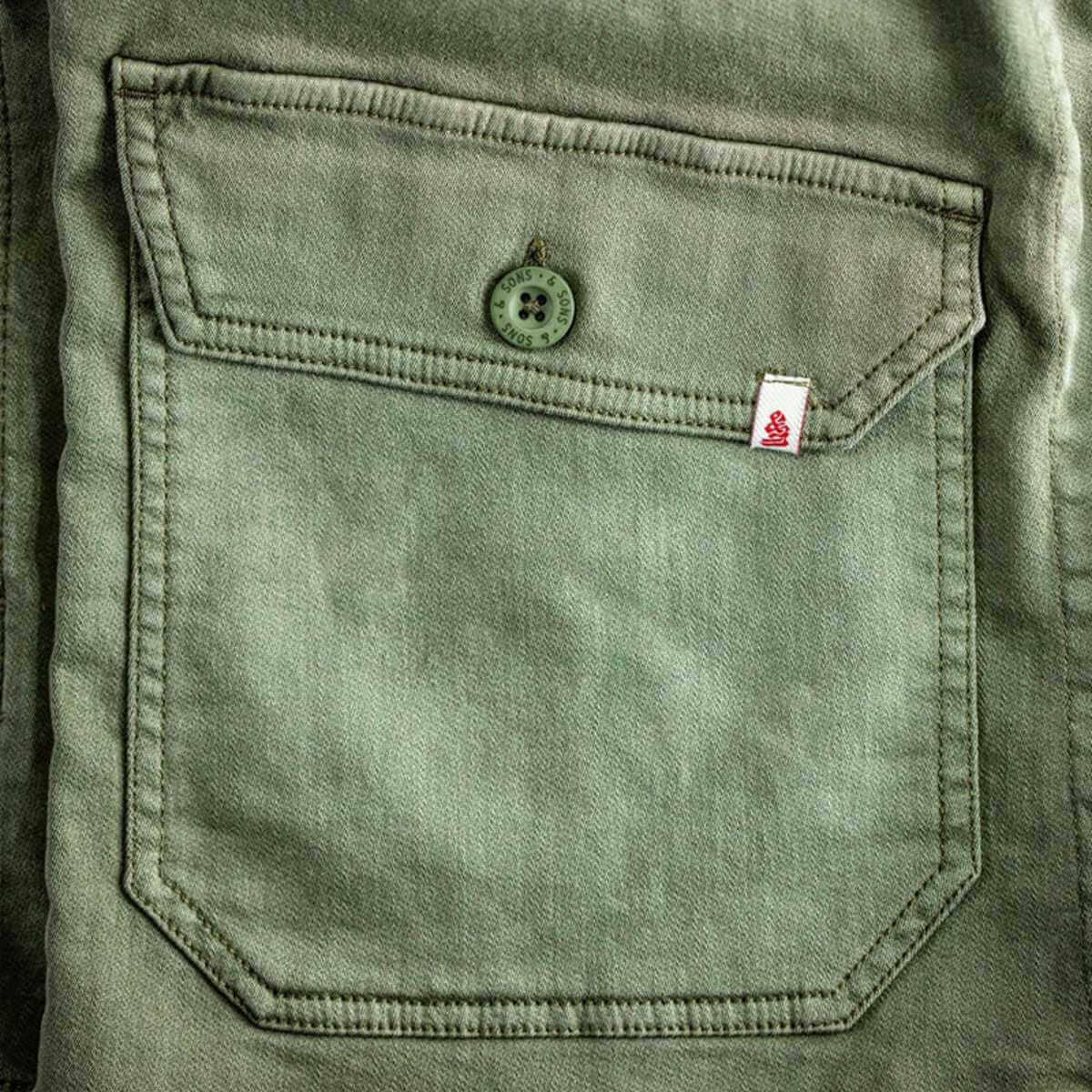 Close-up of a green pocket with a button and label on a garment.