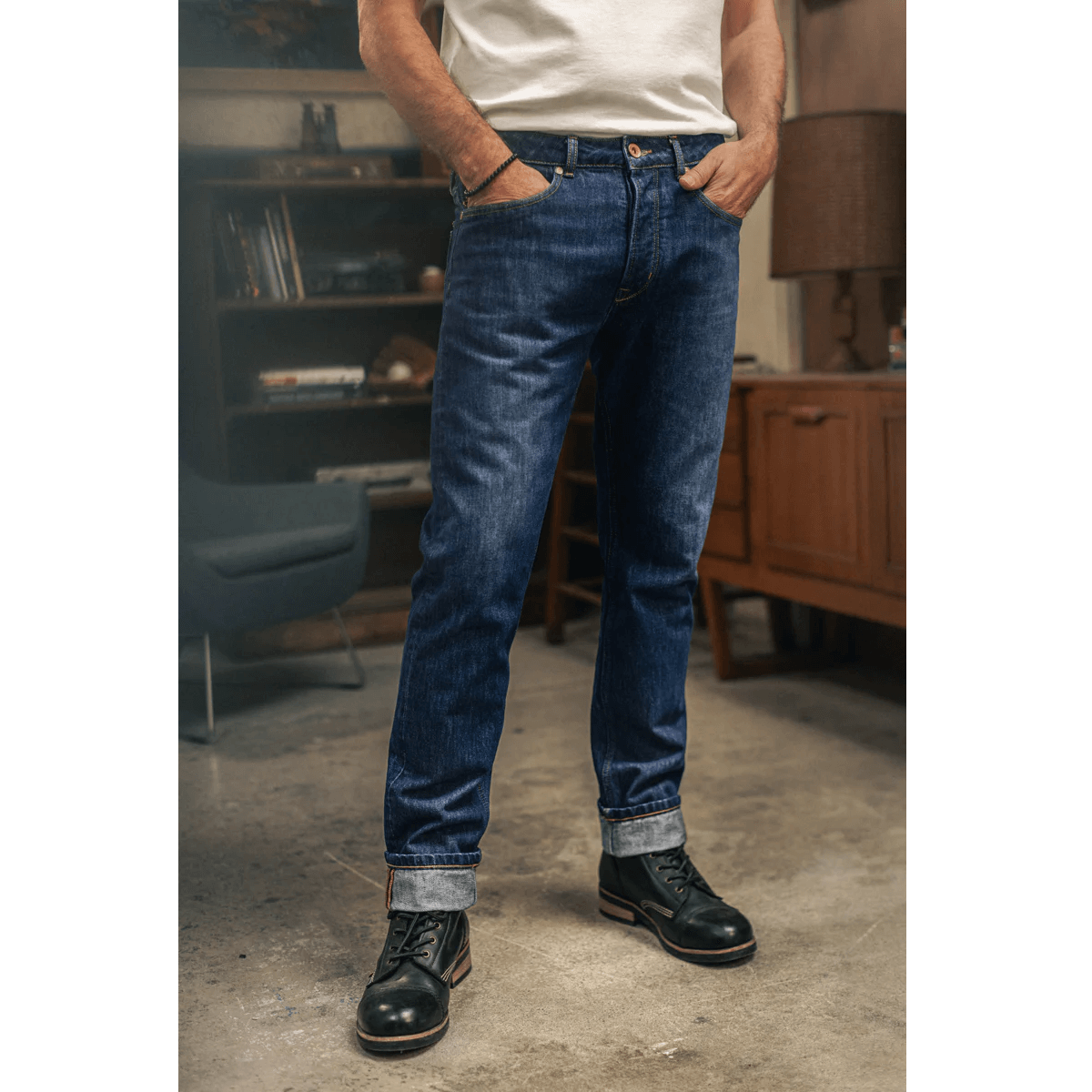 Person wearing blue jeans and black shoes standing in a room with furniture.