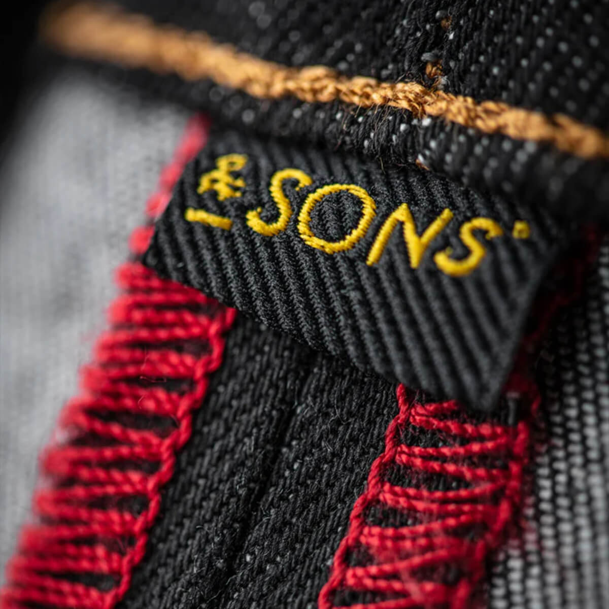 Close-up of a woven label with &amp;SONS text on fabric.