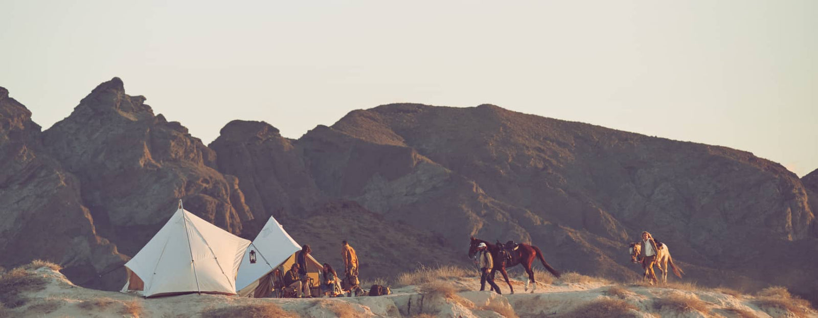 Camping scene with tents and people in a mountainous landscape