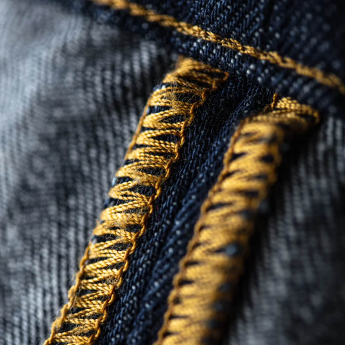 Close-up of blue denim fabric with yellow stitching