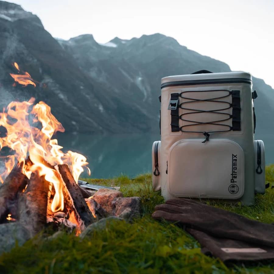 White cooler bag with 'Petromax' logo near a campfire and mountains in the background