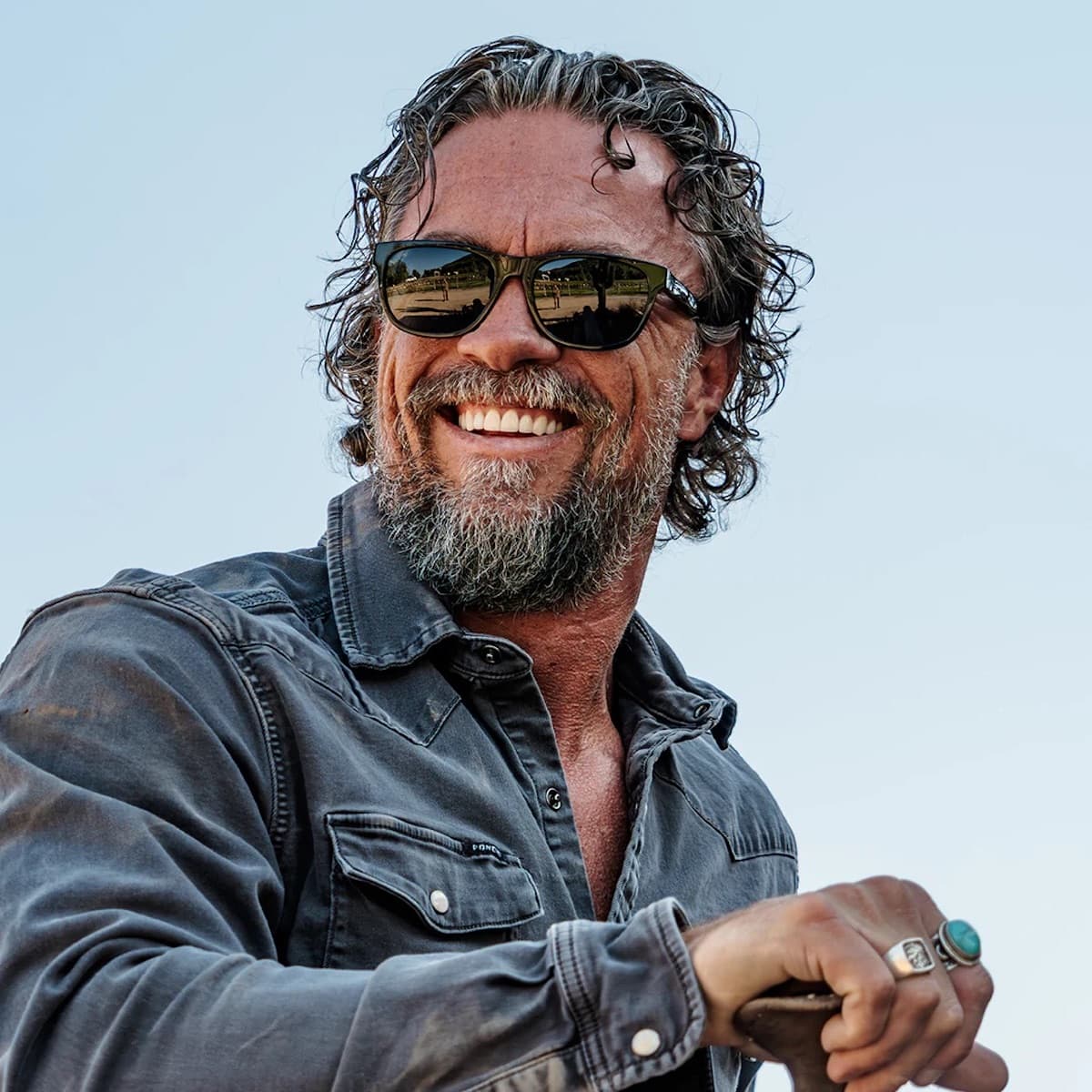 Man with Vallon sunglasses and a beard smiling outdoors