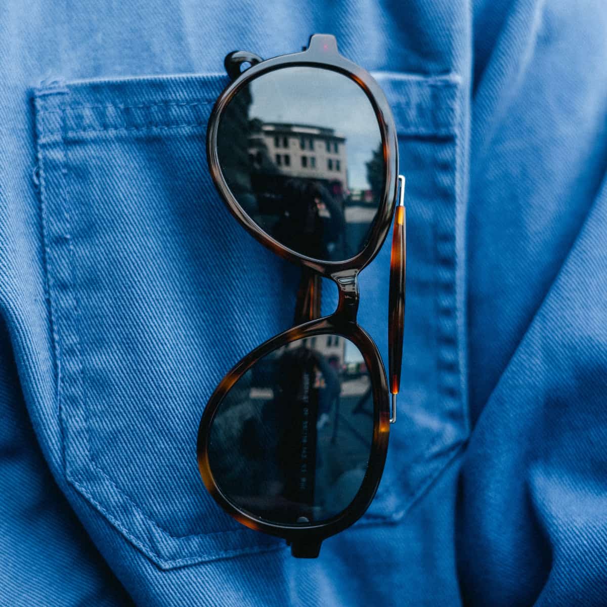 Vallon Brow Bar Aviator Sunglasses with reflective lenses on a blue denim background