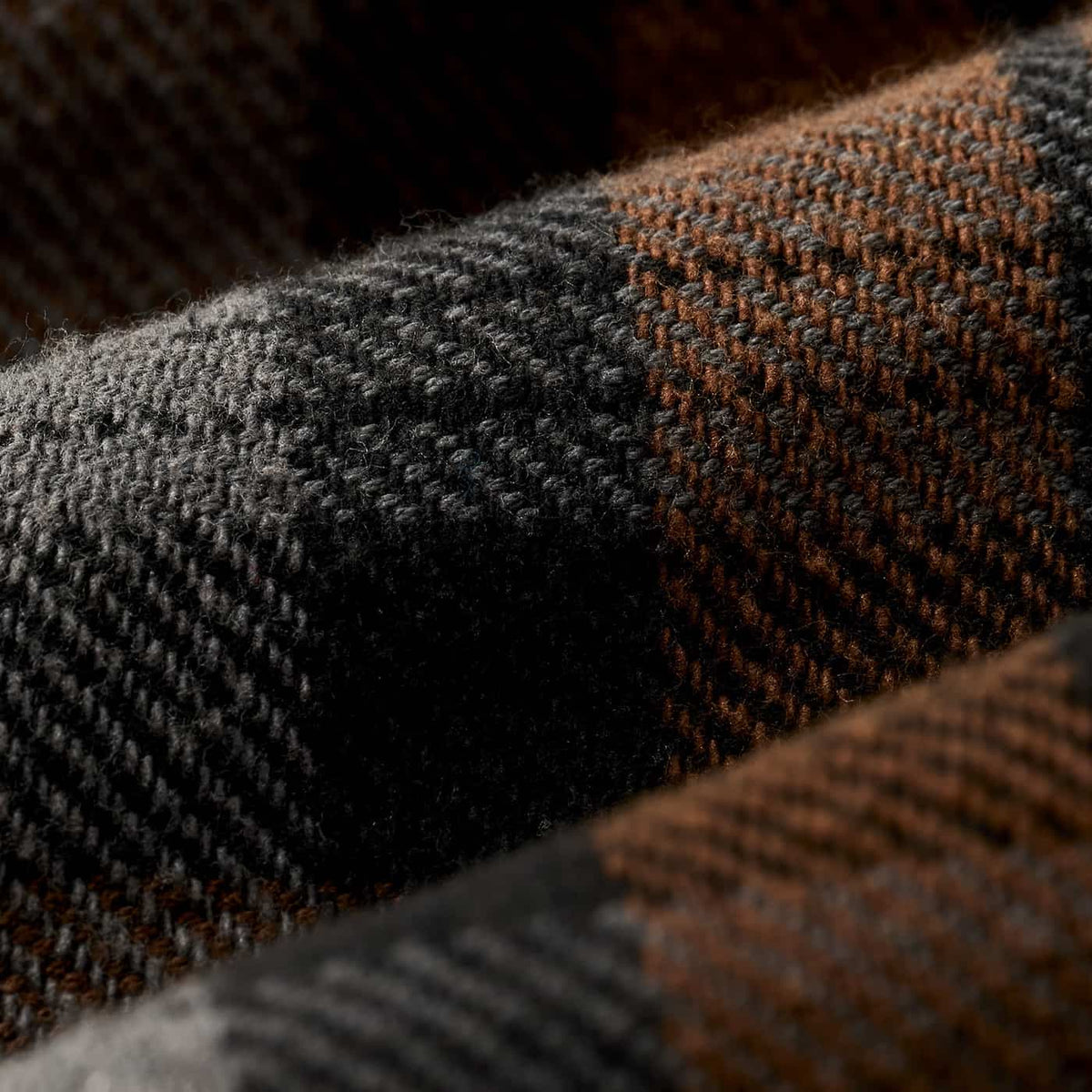 Close-up of a textured plaid fabric with a dark charcoal gray and warm brown check pattern.