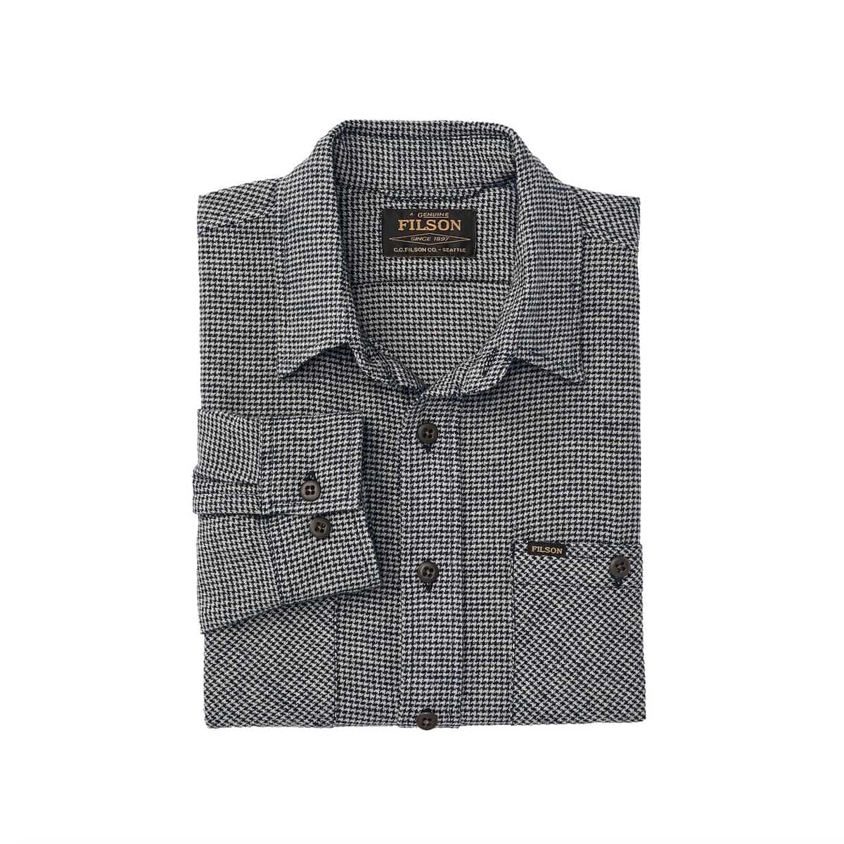A folded long-sleeve button-up shirt by Filson, featuring a small-scale black and white micro-check pattern, with a pointed collar, button front, and a chest pocket.