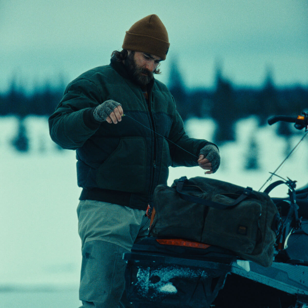 Man in winter clothing with a backpack near a vehicle in a snowy landscape