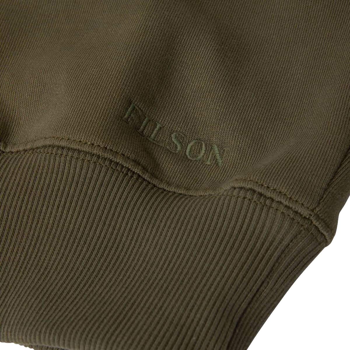 Close-up of an olive green ribbed sweatshirt cuff with tonal embroidered 'FILSON' branding.