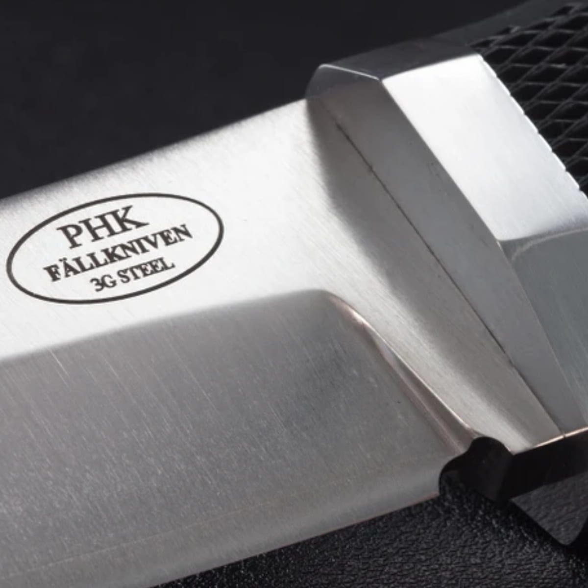 Close-up of a PHK Fällkniven 3G Steel knife showing the brushed stainless steel blade with a black textured handle and the PHK logo.