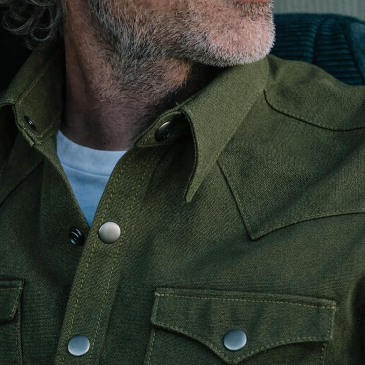 Close-up of a person wearing a green jacket with a buttoned collar.