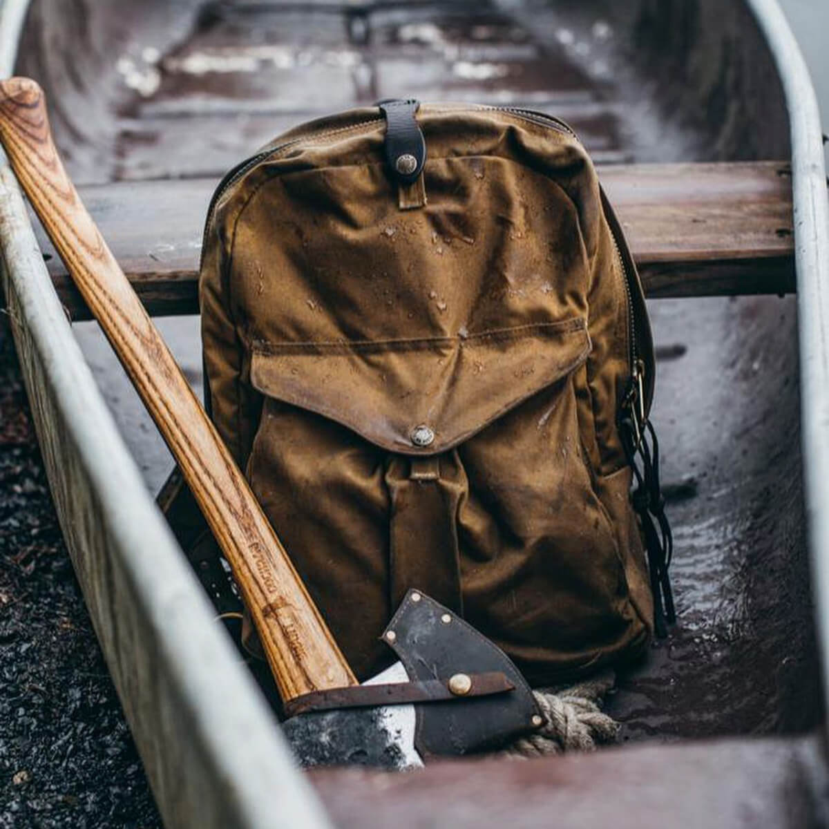 Brown backpack with axe on a wooden surface