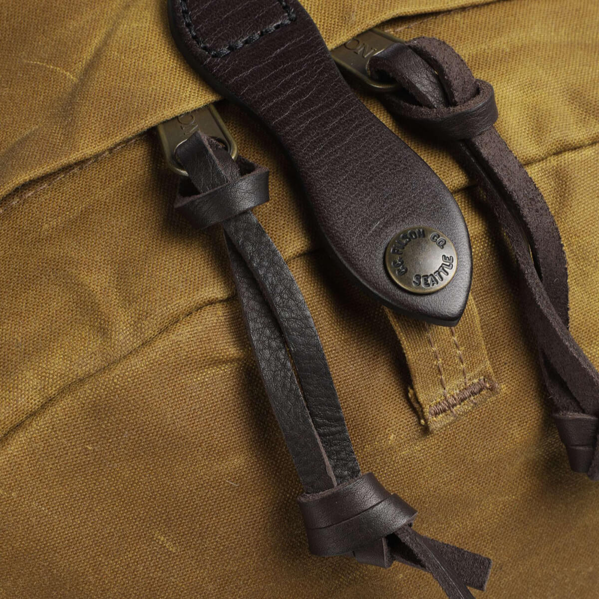 Close-up of a brown leather strap with a metal buckle on a brown fabric background