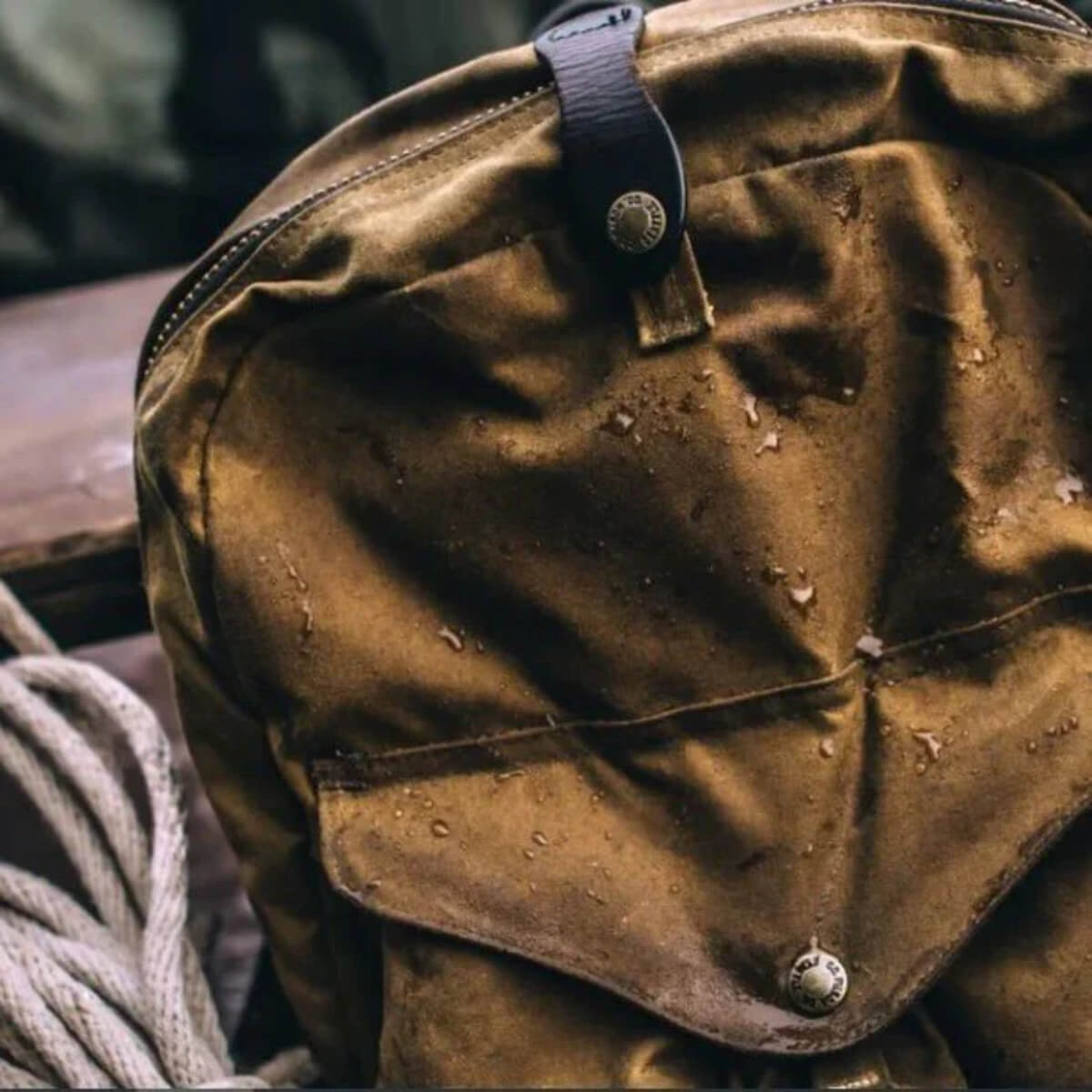 Brown leather bag with visible wear and buttons, surrounded by ropes on a wooden surface.