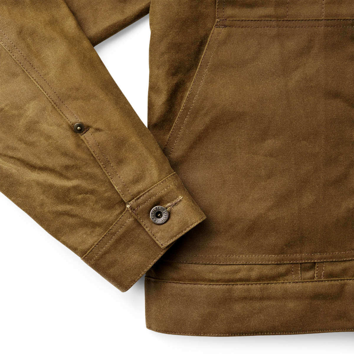 Close-up of a brown Filson jacket with a button on a white background