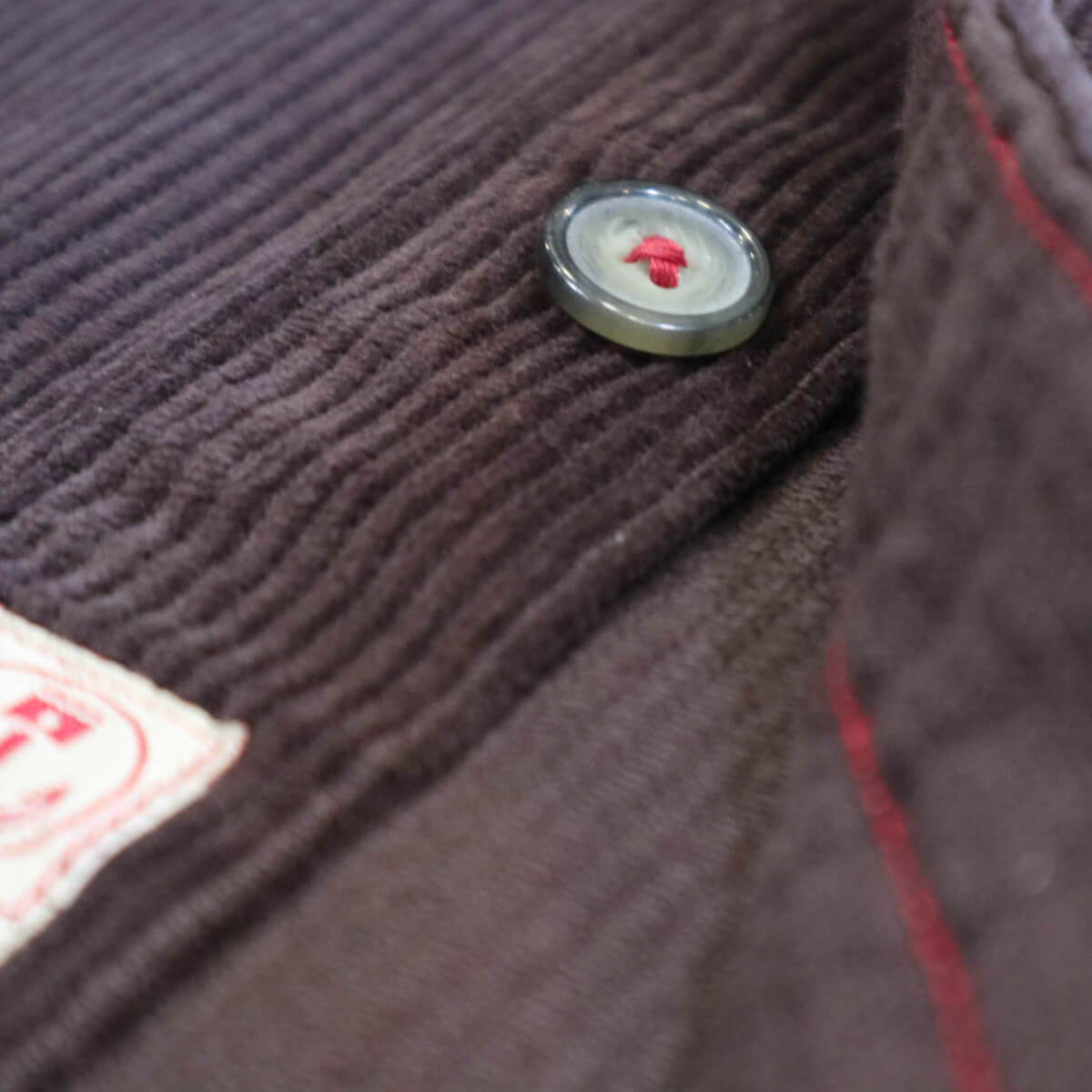Close-up of a textured fabric surface with a button featuring a red heart design.
