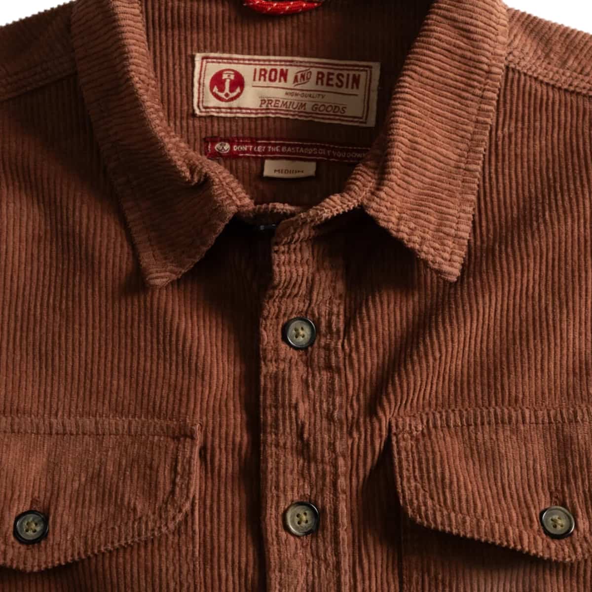 Close-up of a brown corduroy button-up shirt with a visible Iron and Resin neck label and two chest pockets.