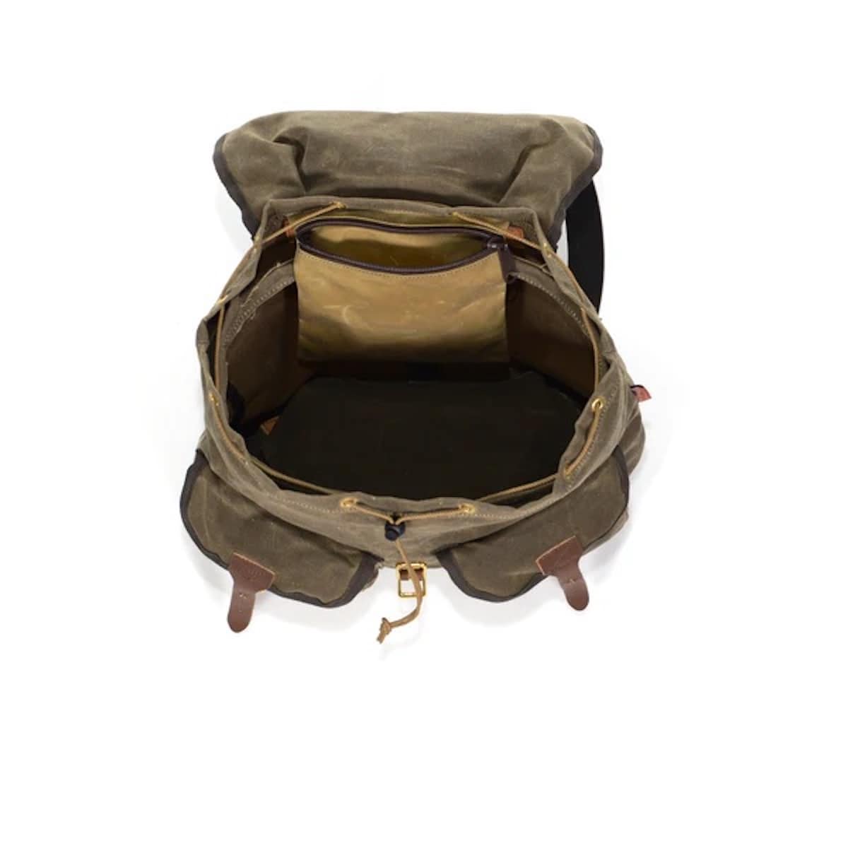 An open canvas backpack in an olive green color, showing its interior compartments, tan lining, and brown leather-like trim details, set against a plain white background.