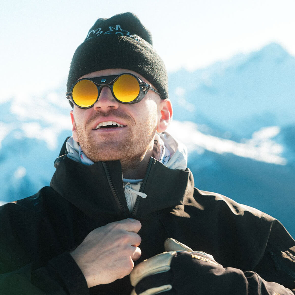 Man wearing sunglasses and a beanie with mountains in the background
