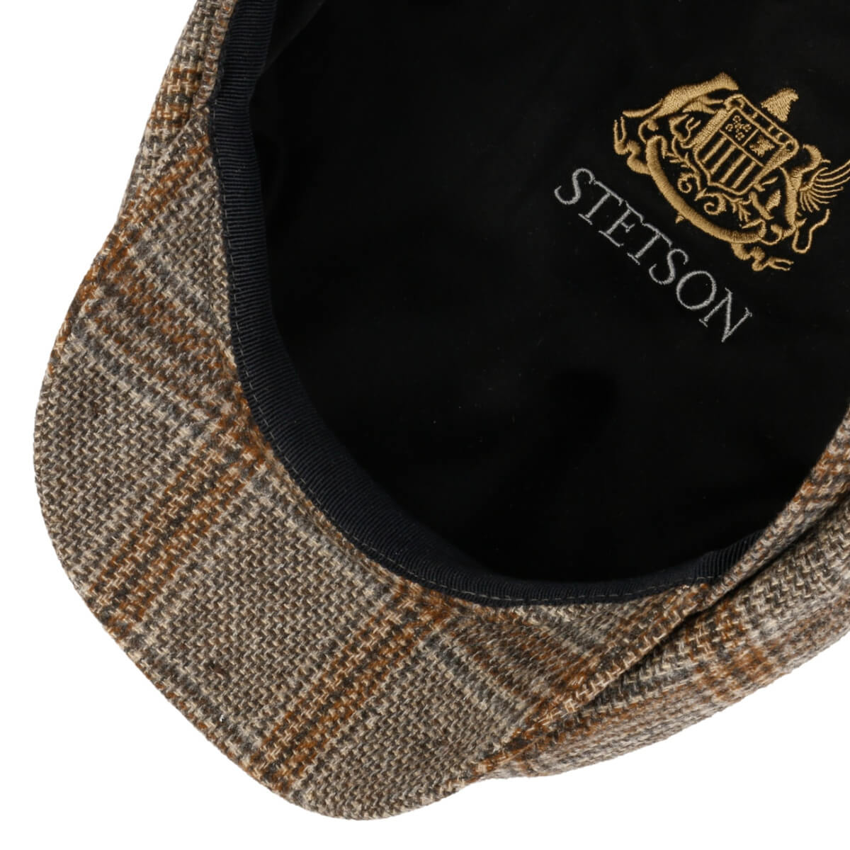 Close-up of a Stetson cap with plaid brim and embroidered logo.