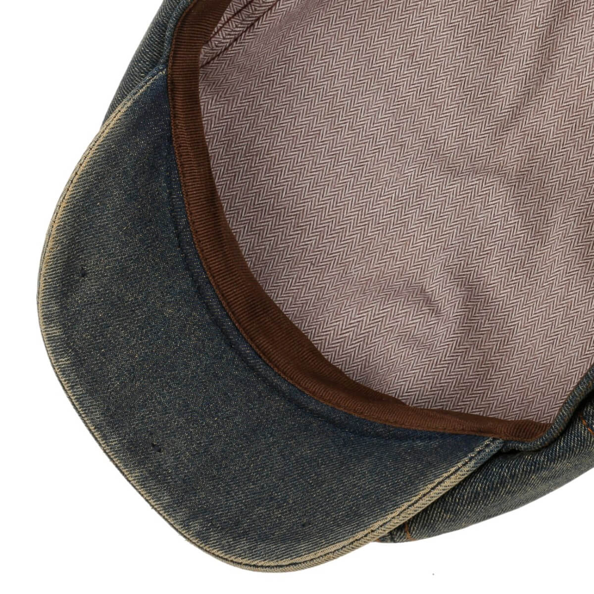 Close-up of a denim cap with brown interior lining on a white background