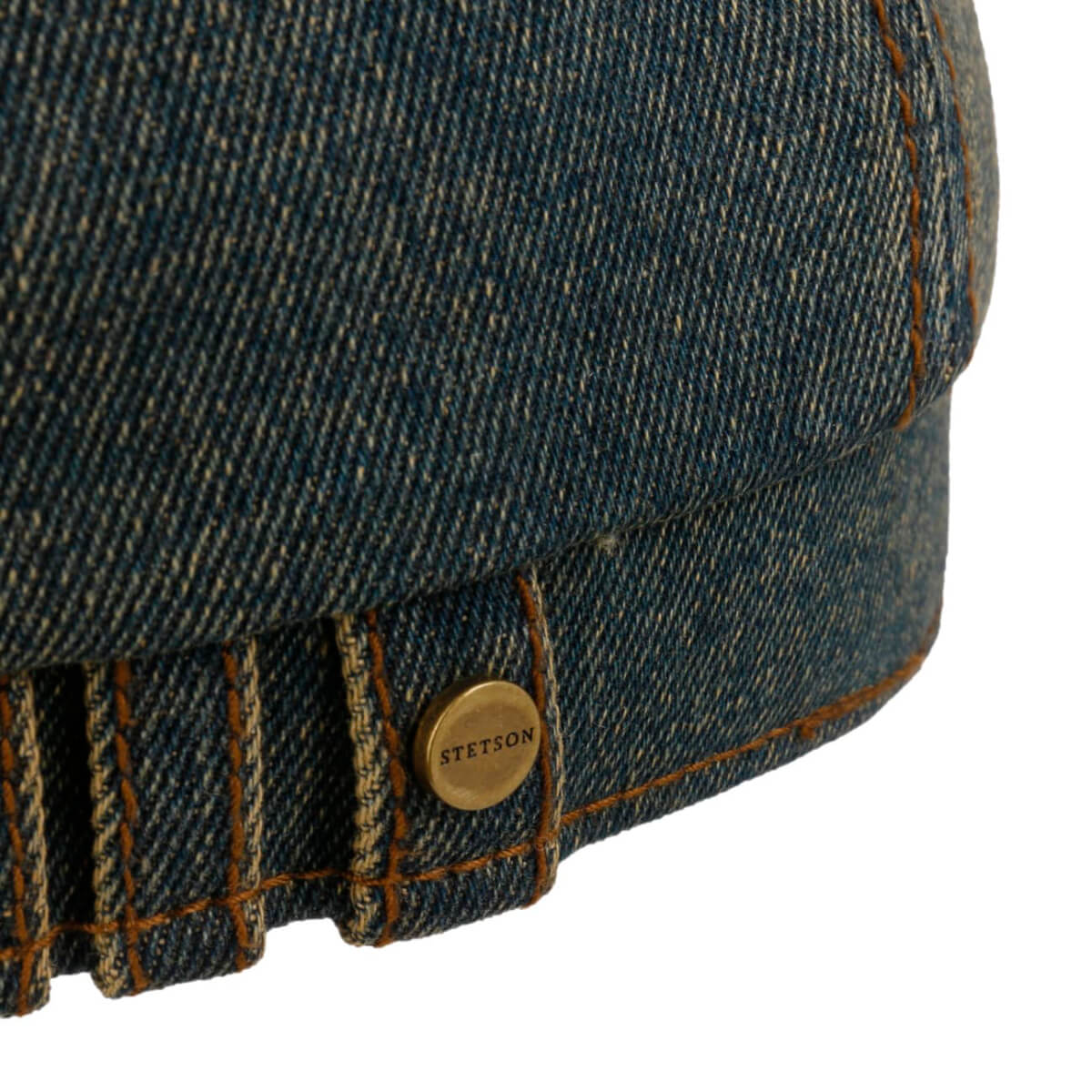 Close-up of a denim cap with a gold button featuring 'Stetson' branding on a white background.