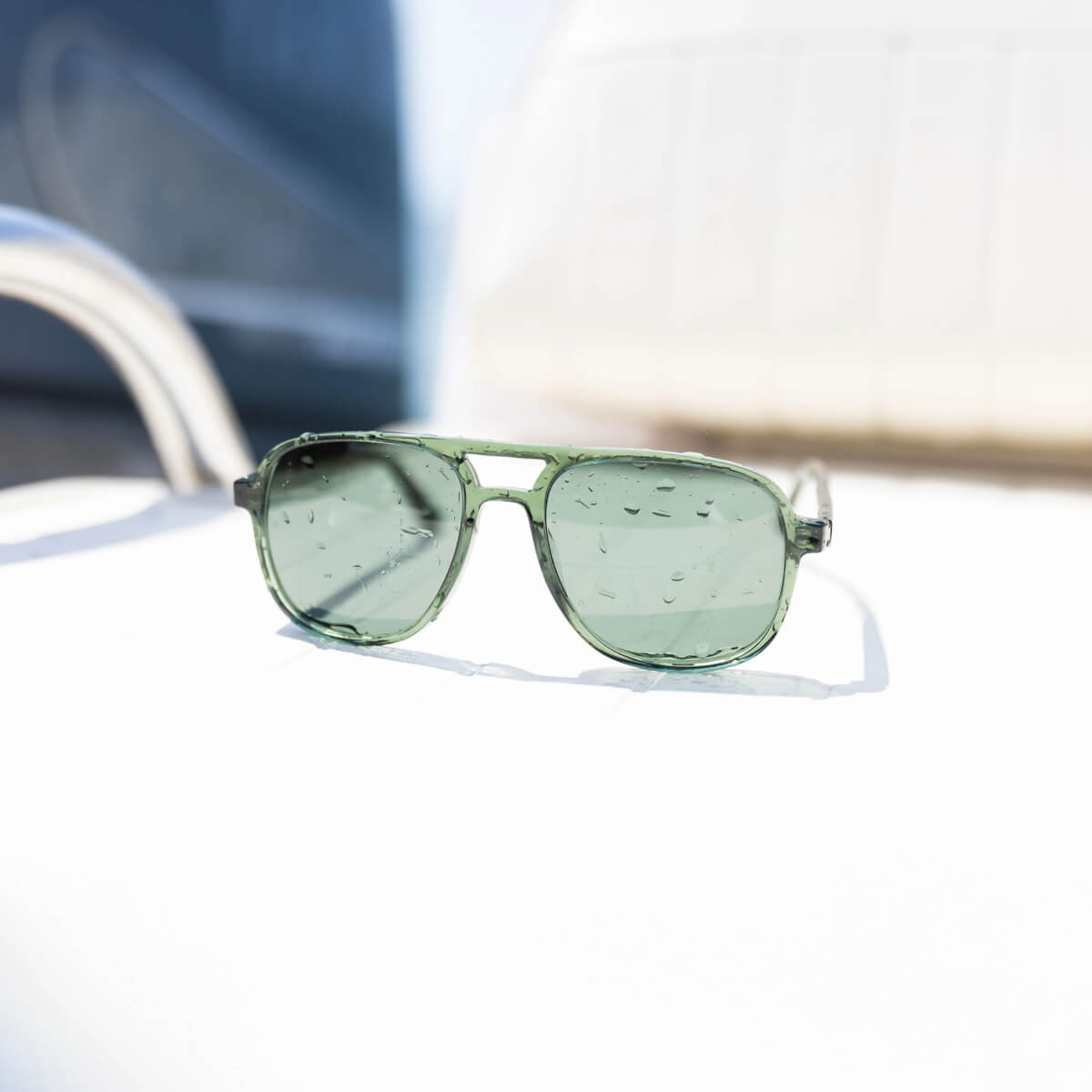 Green sunglasses on a reflective surface with blurred background
