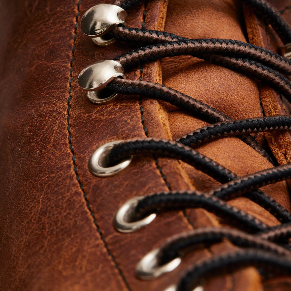 Close-up of brown leather boot with black laces and metal eyelets