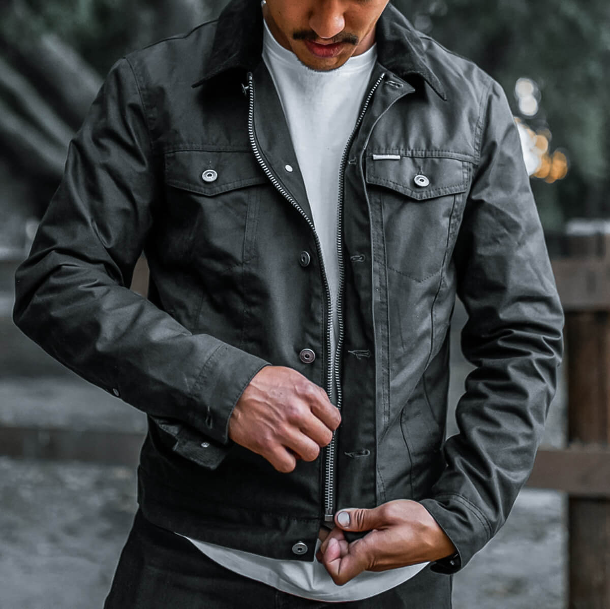 Person wearing a dark green jacket with a blurred background