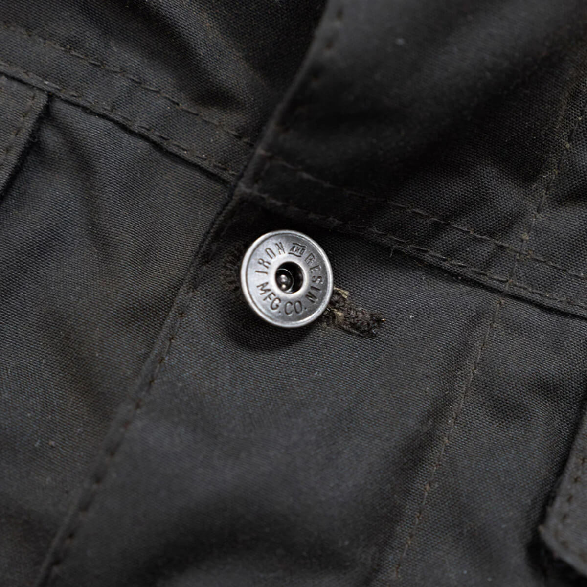 Close-up of a button on a black jacket with a brand logo.