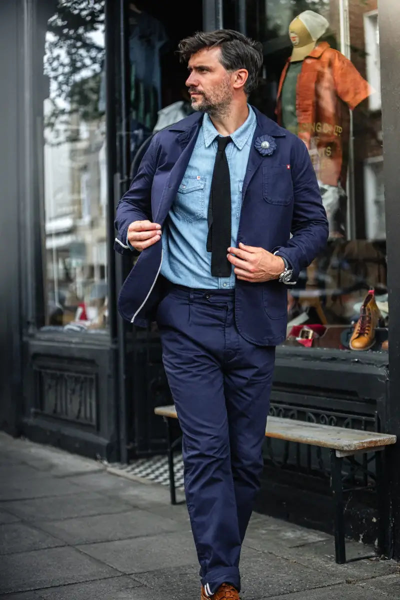 Man in a blue suit with a tie walking on a street.