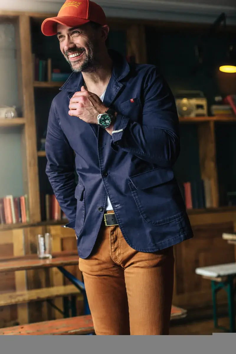 Man wearing a navy jacket and orange cap in an indoor setting