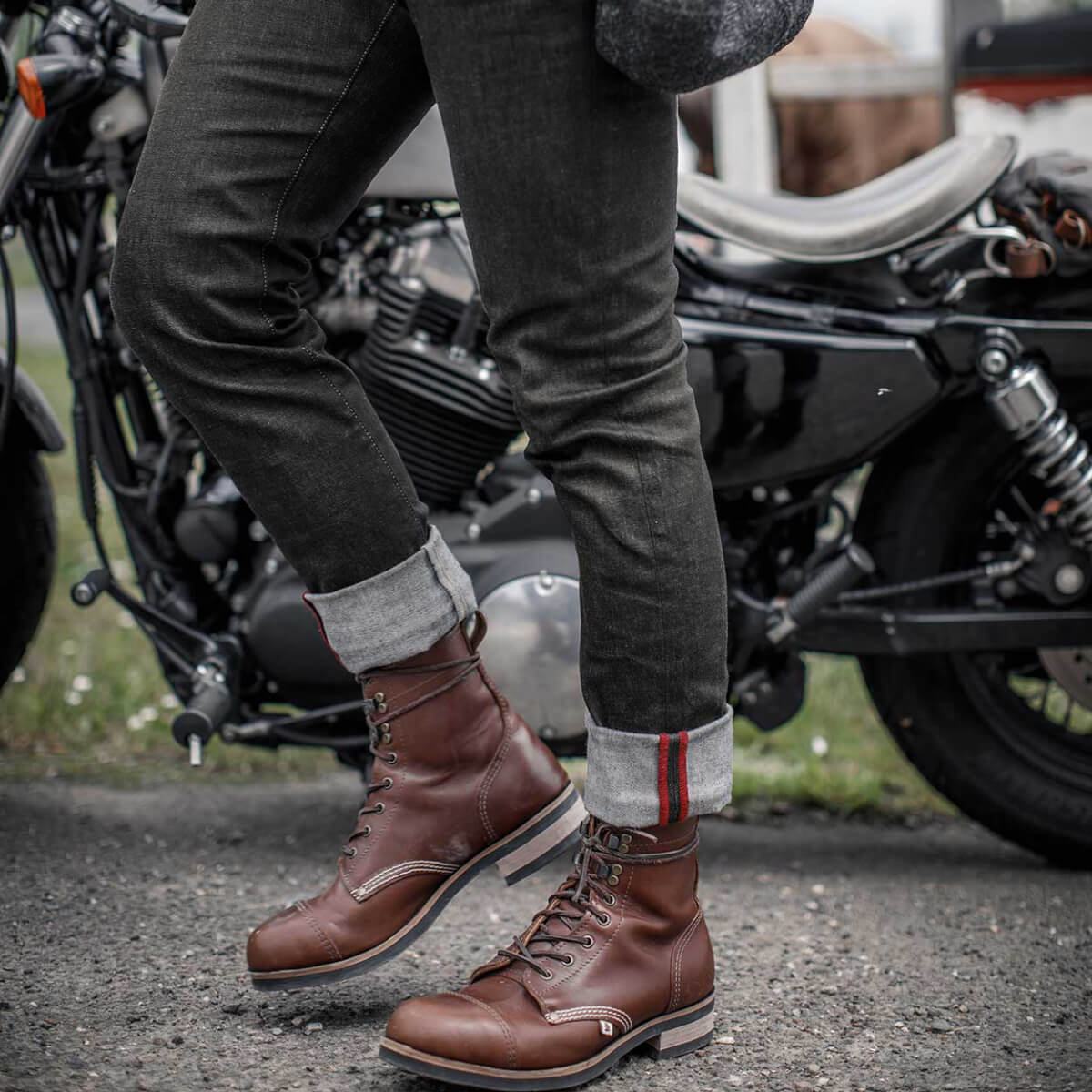 Person wearing brown leather boots with a motorcycle in the background