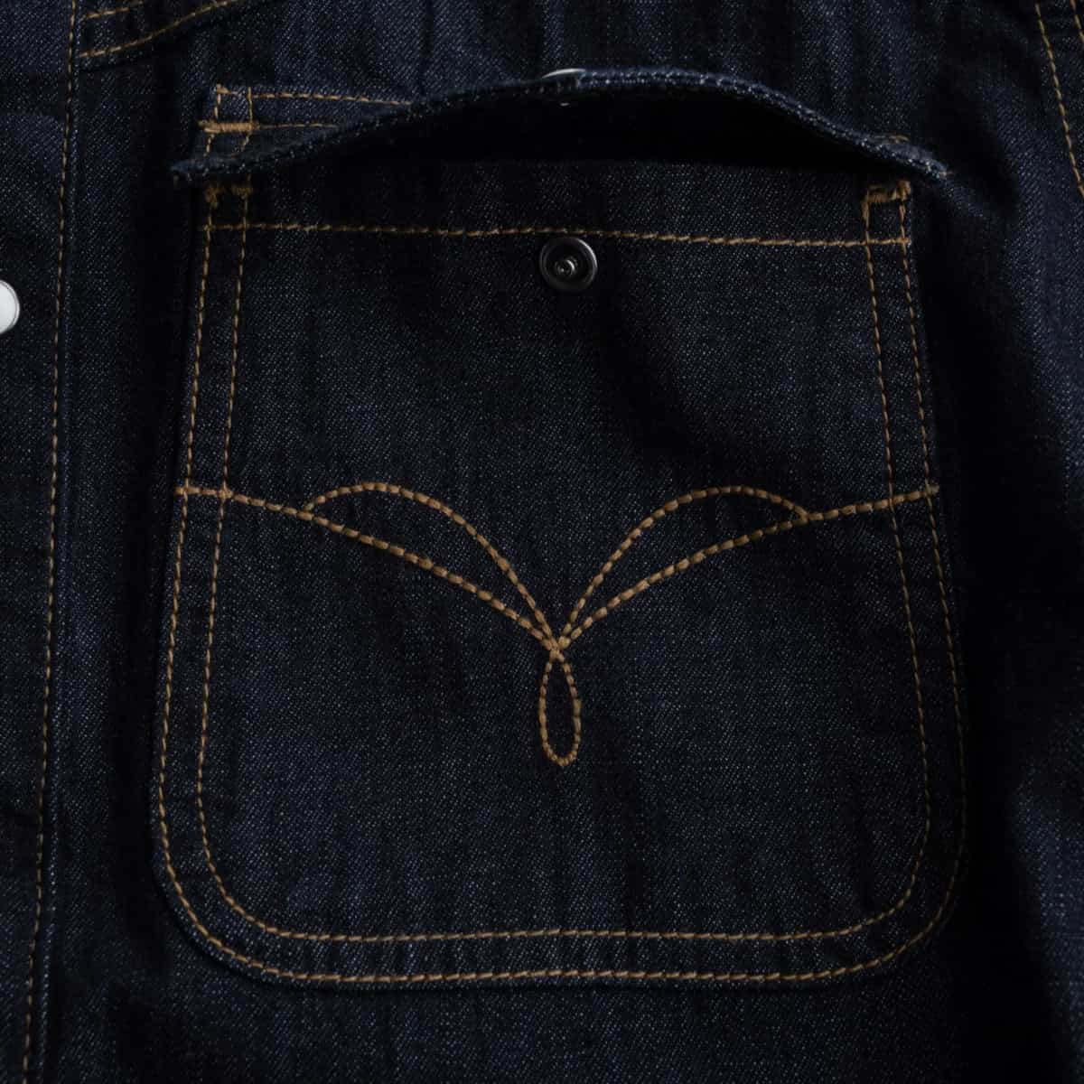 Close-up of a dark indigo denim pocket with contrast tan stitching and a small metal snap closure.