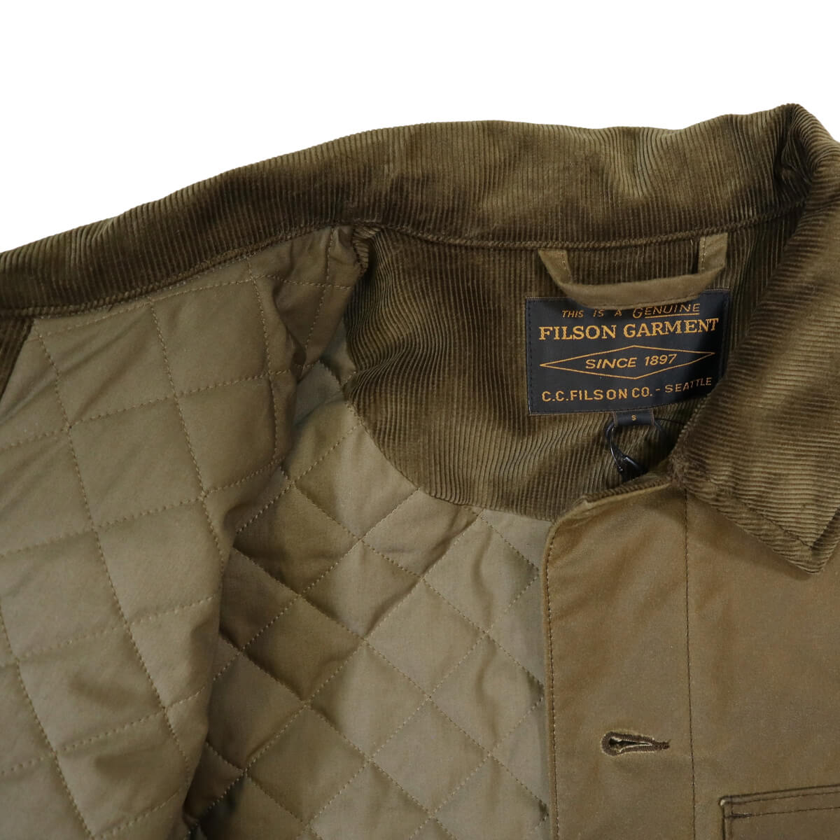 Close-up of a brown quilted jacket with Filson Garment label on a white background