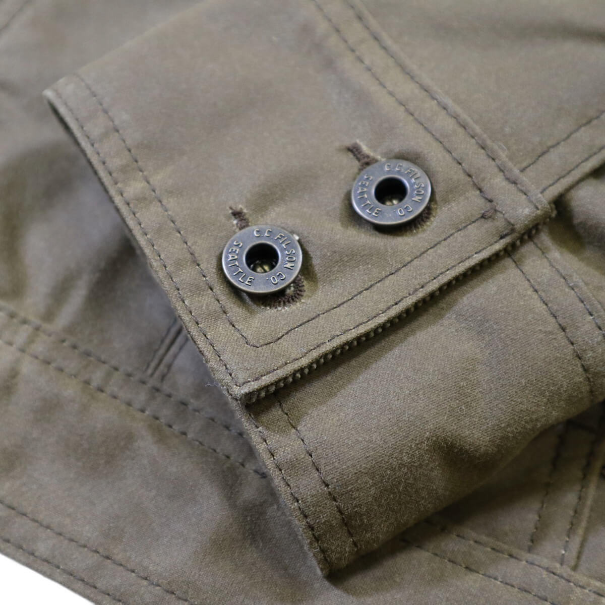 Close-up of a beige jacket with buttons on a matching fabric background