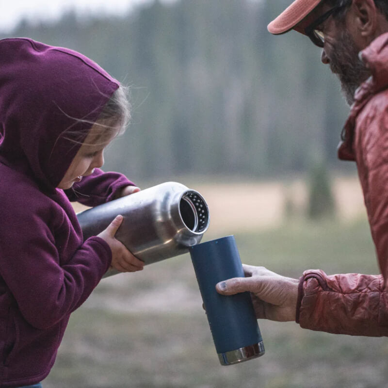 Person and child holding insulated cups outdoors