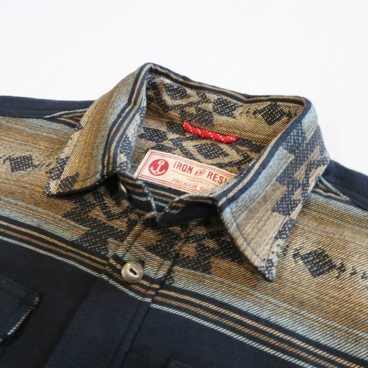 Close-up of a patterned shirt collar with a brand label on a white background