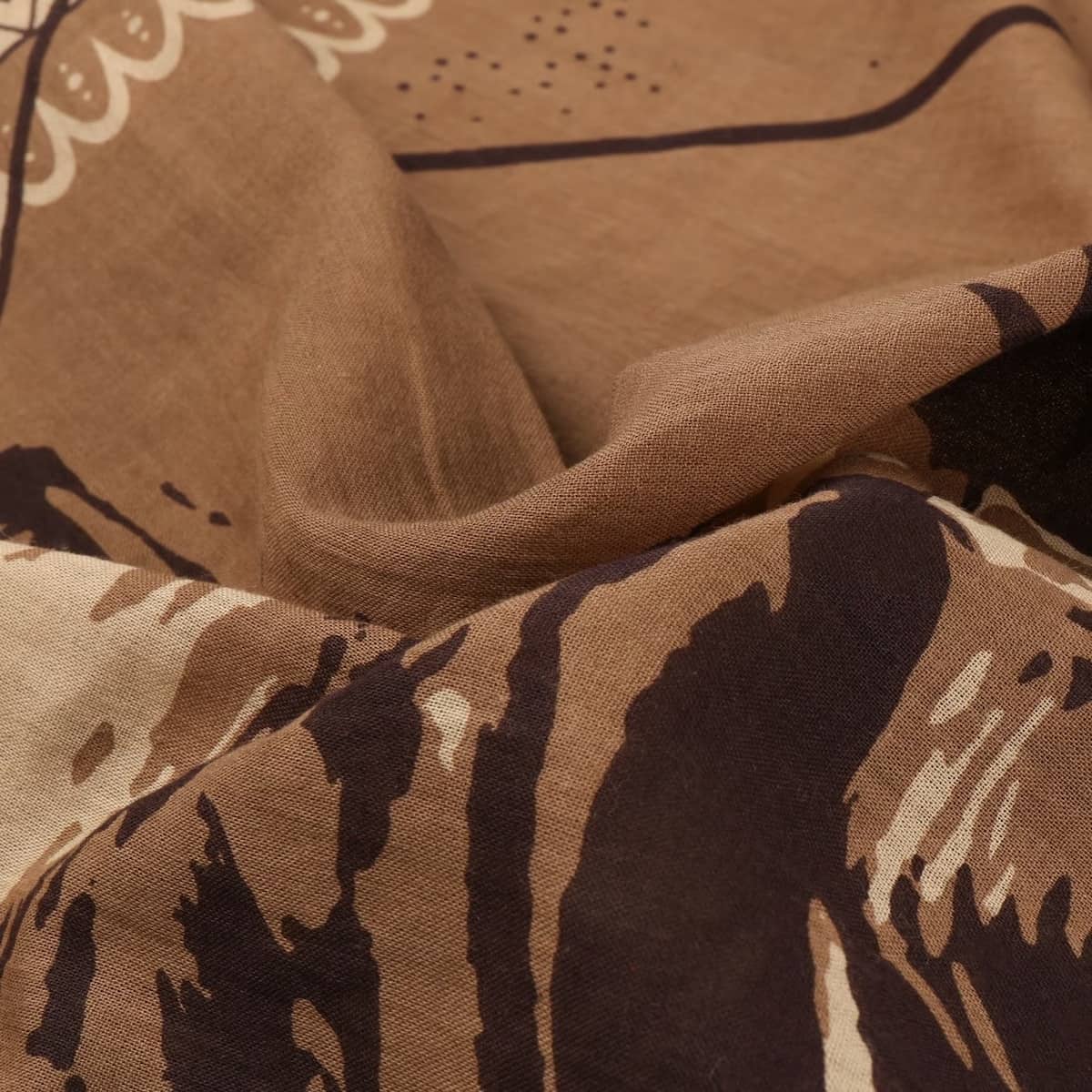 A close-up of draped Stetson bandana fabric with a tan and brown abstract pattern, showing the material texture and folds.