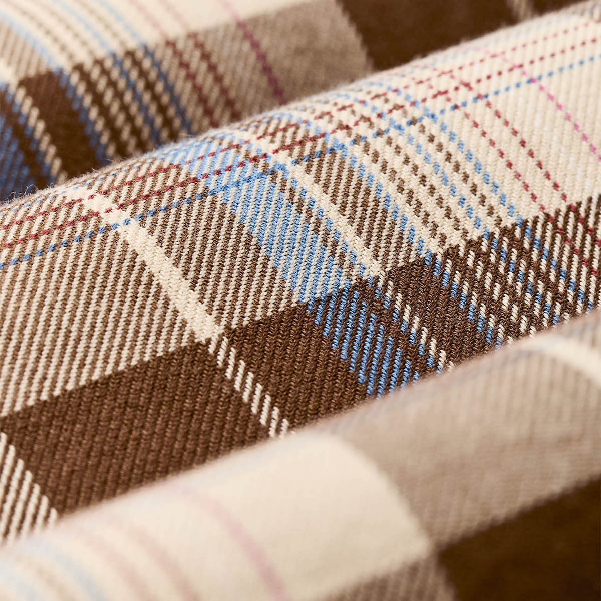 Close-up of plaid fabric with brown, blue, and beige colors.