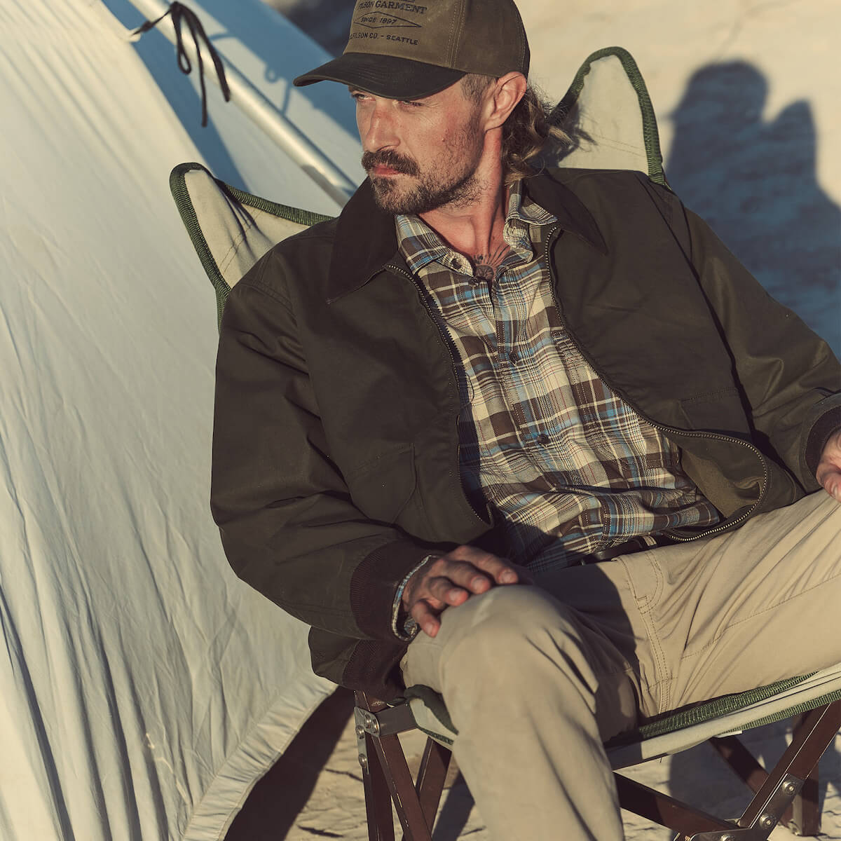 Man sitting in a chair outdoors with a tent in the background