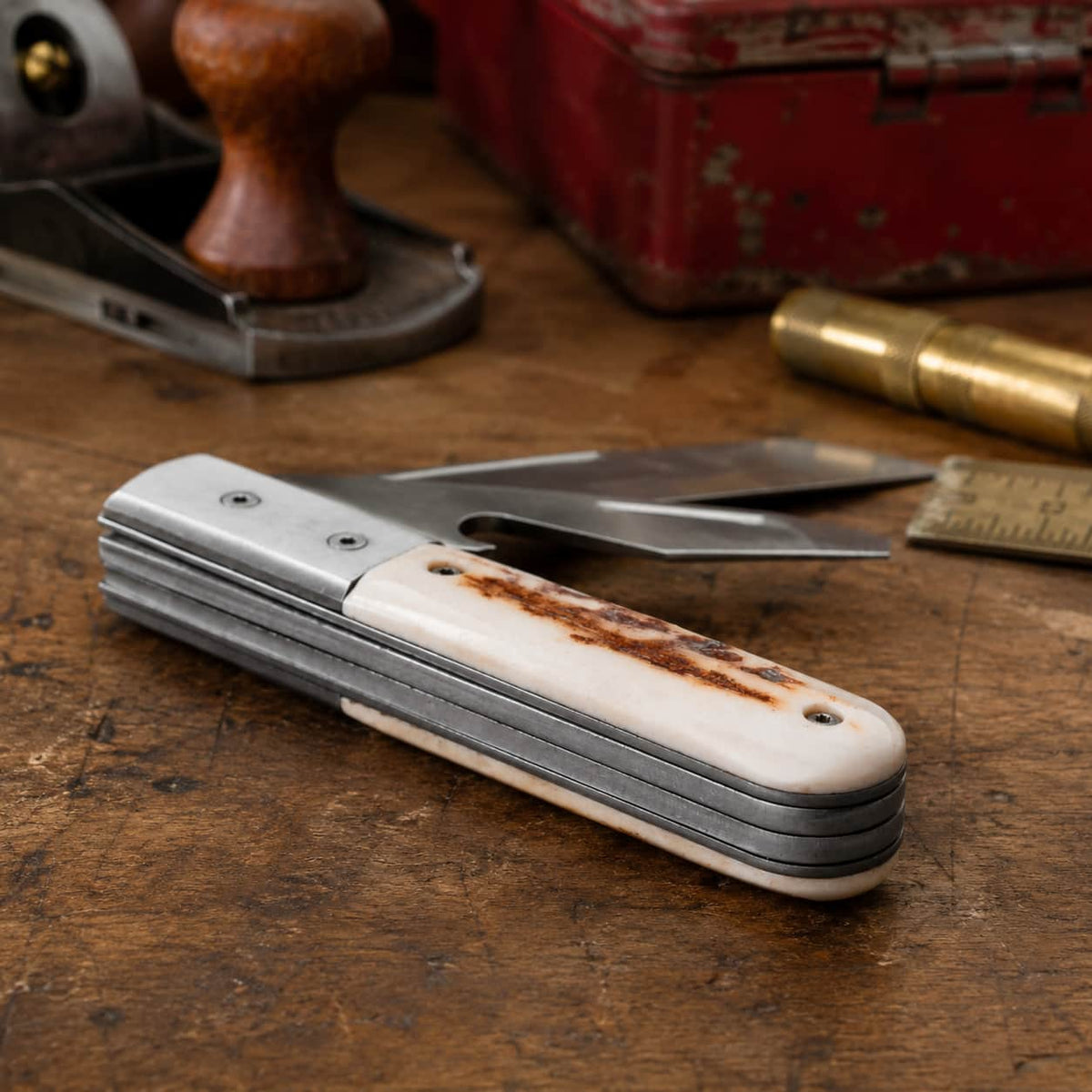 Pocket knife with wooden handle on a wooden surface with tools in the background