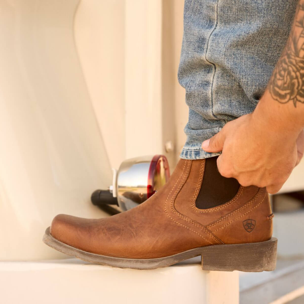 Person wearing a brown leather boot with a blurred background