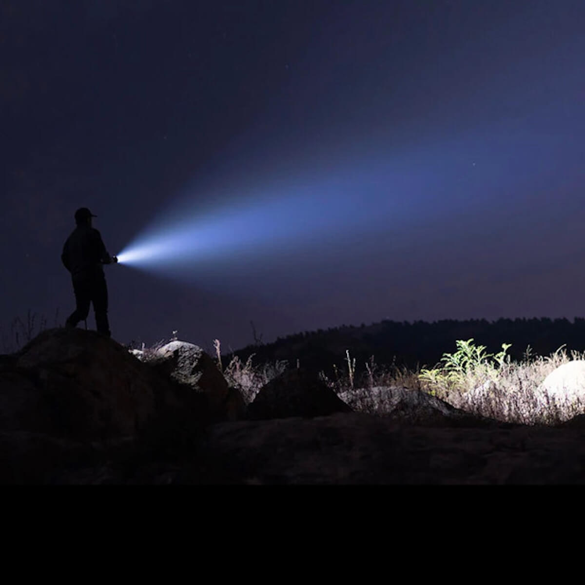 Person using a flashlight in a dark outdoor setting