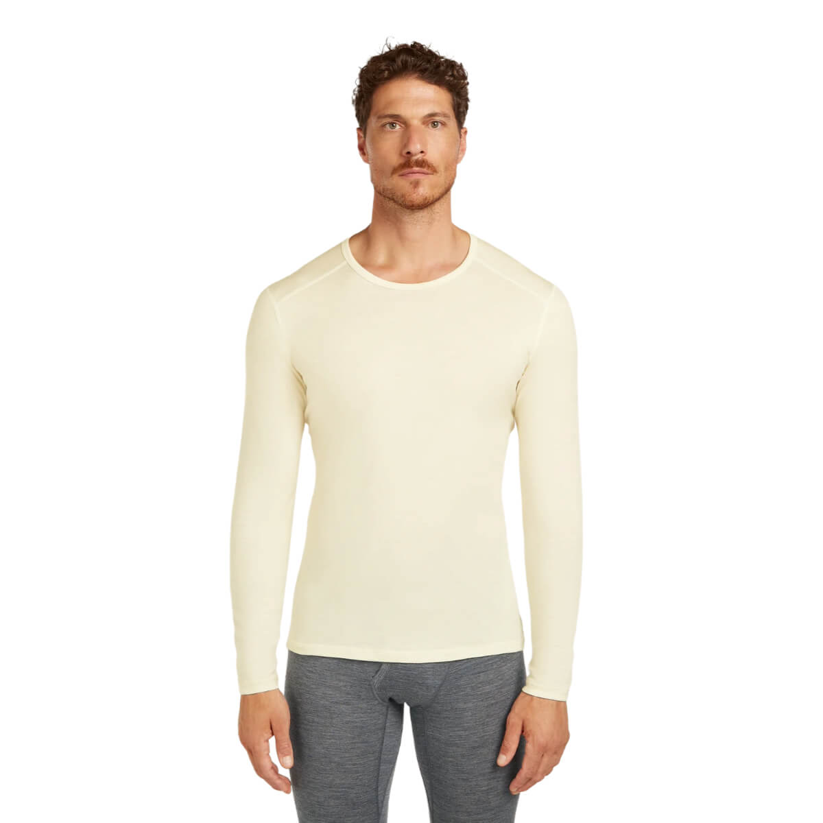 Man wearing a cream long-sleeve shirt and gray pants on a white background
