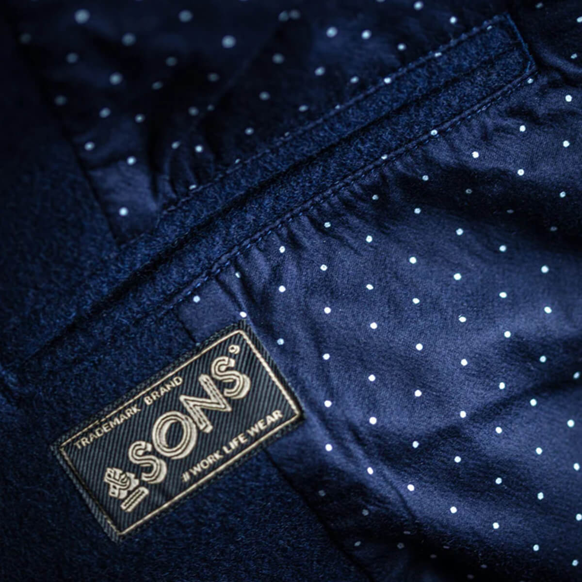 Close-up of a navy blue garment with white polka dots and a visible brand label.
