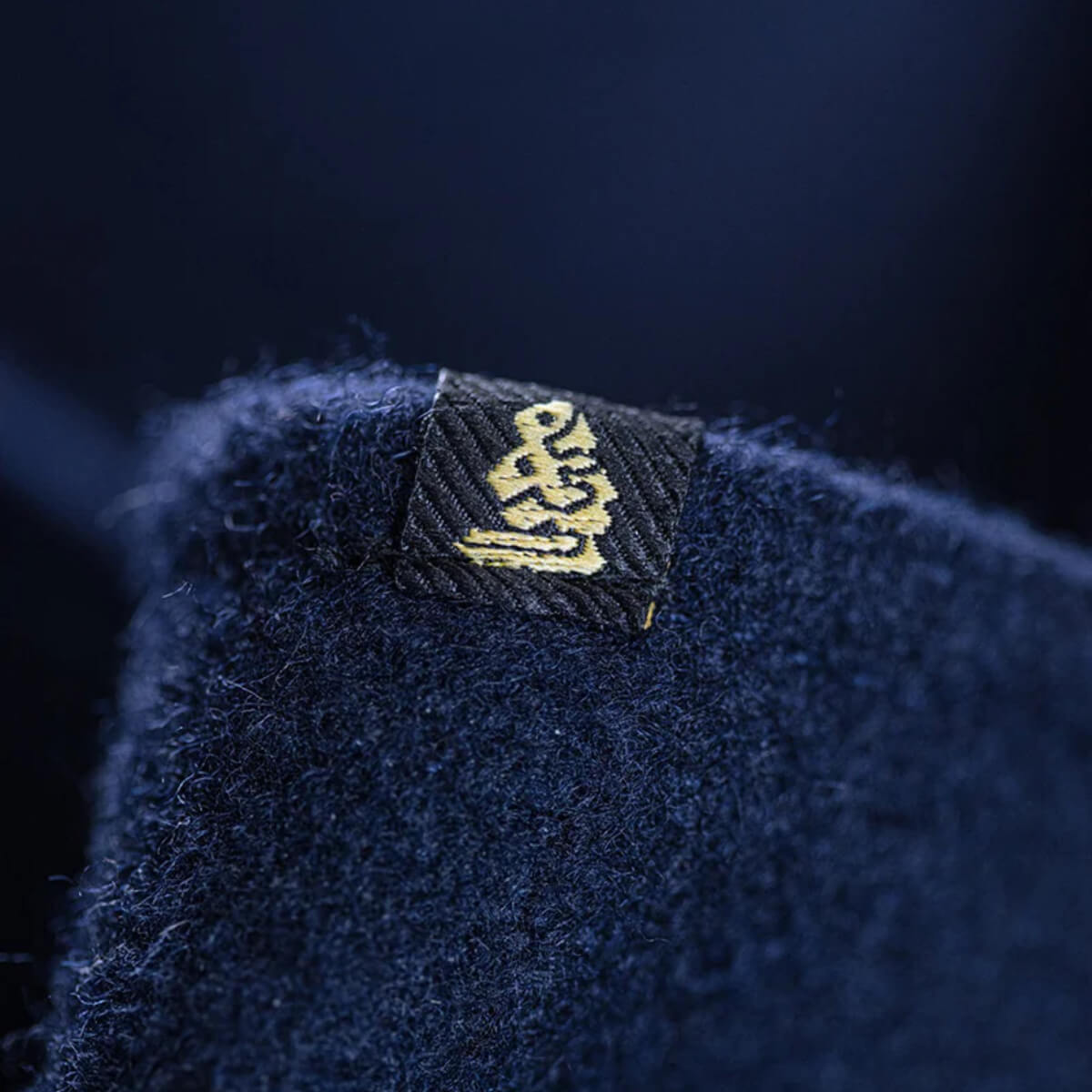 Close-up of a blue textured fabric with a brand logo on a dark background